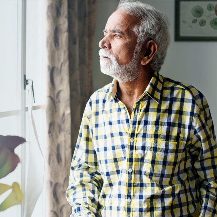 Elderly Indian man looking out a window