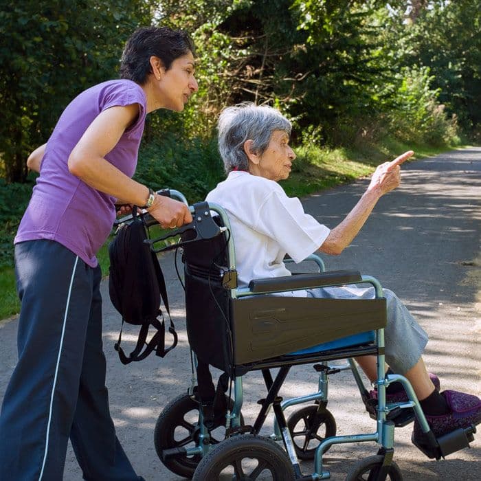 Woman pushing an elderly woman in wheelchair outdoors
