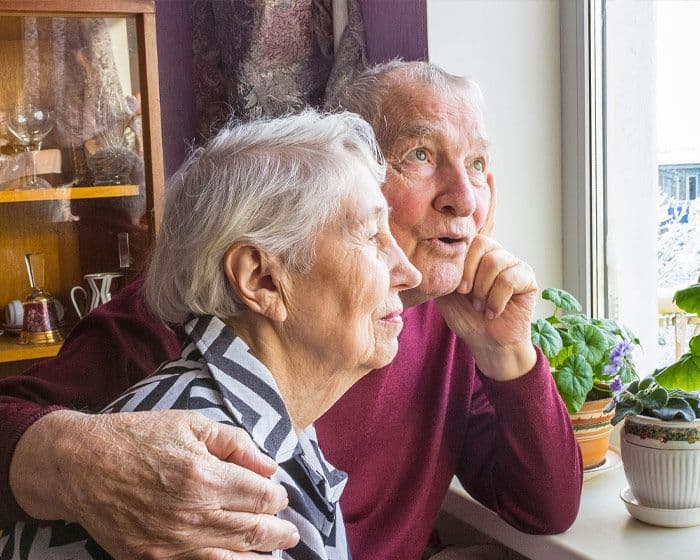 An elderly couple looking out the window