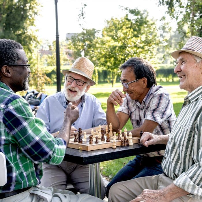 A group of elderly friends playing chess outdoors